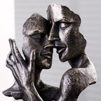 Bronze sculpture of two abstract faces embracing against a gray background
