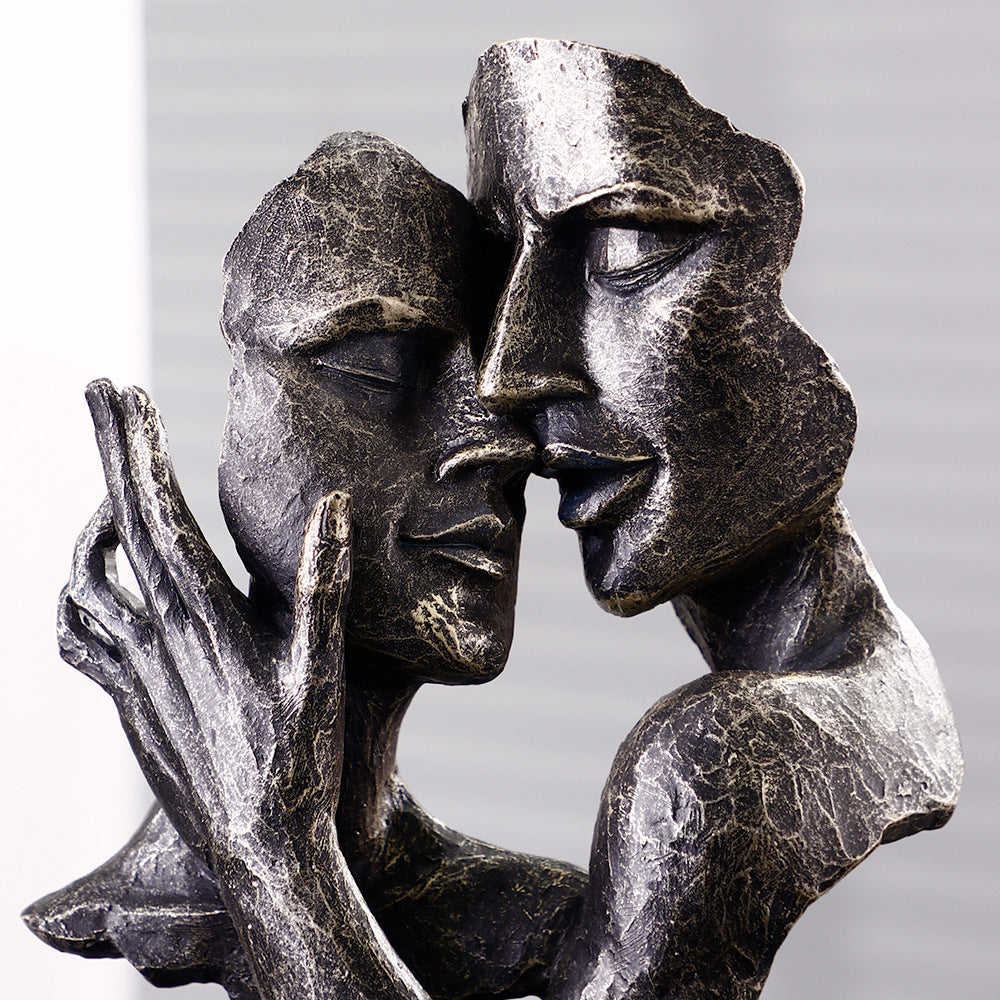 Bronze sculpture of two abstract faces embracing against a gray background
