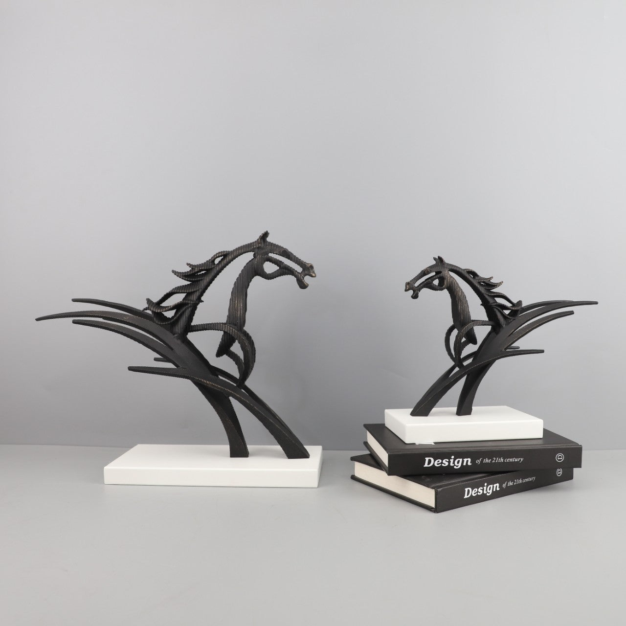 Two black horse sculptures on white bases against a gray background
