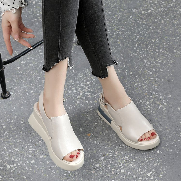 White open-toe sandals worn on a gray pavement