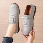 Light gray sneakers held by a hand on a beige background
