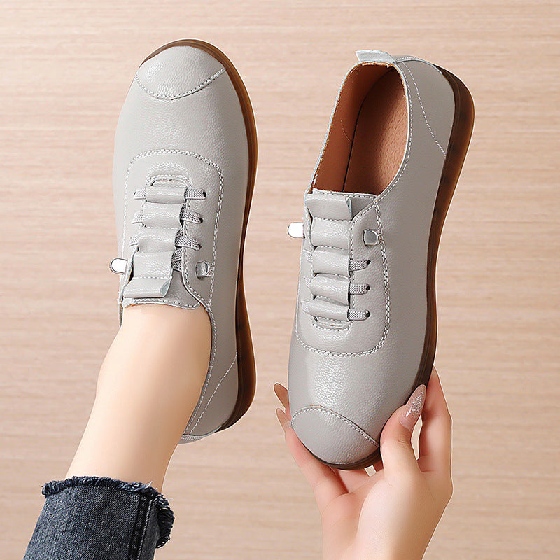 Light gray sneakers held by a hand on a beige background