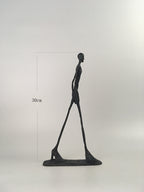 Black abstract sculpture of a figure on a white background with measurement label