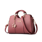 Pink handbag with star charm and gold accents on a white background