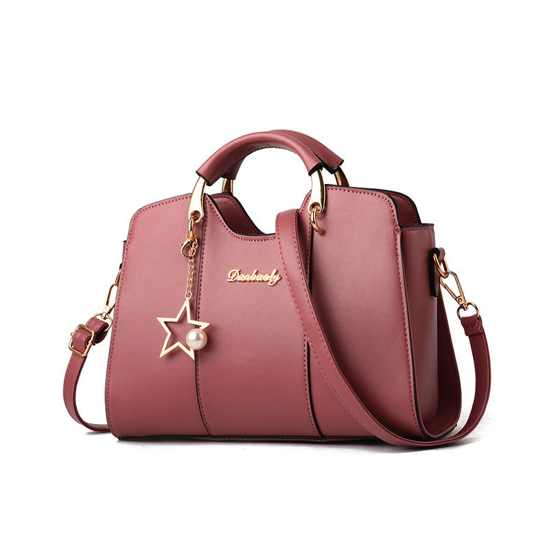Pink handbag with star charm and gold accents on a white background