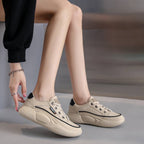Beige sneakers worn by a person sitting on a gray surface