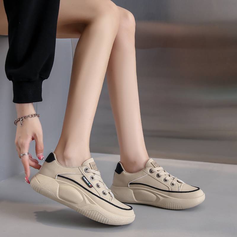 Beige sneakers worn by a person sitting on a gray surface