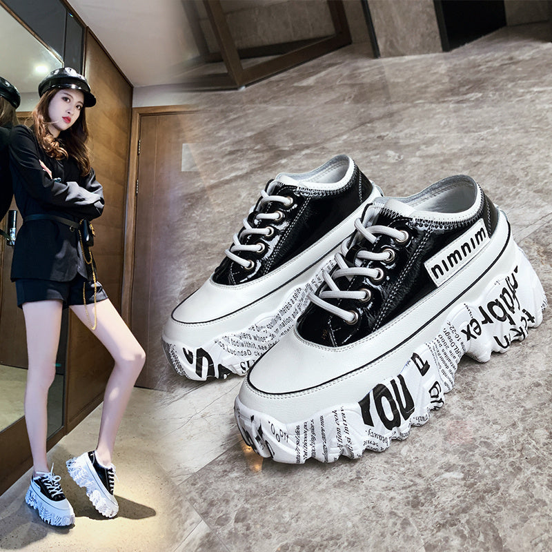 Black and white sneakers with text design on a gray floor.