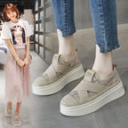 Beige platform sneakers worn by a person, with a blurred background of a woman in a store.