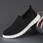 Black slip-on shoe with white sole on a dark background