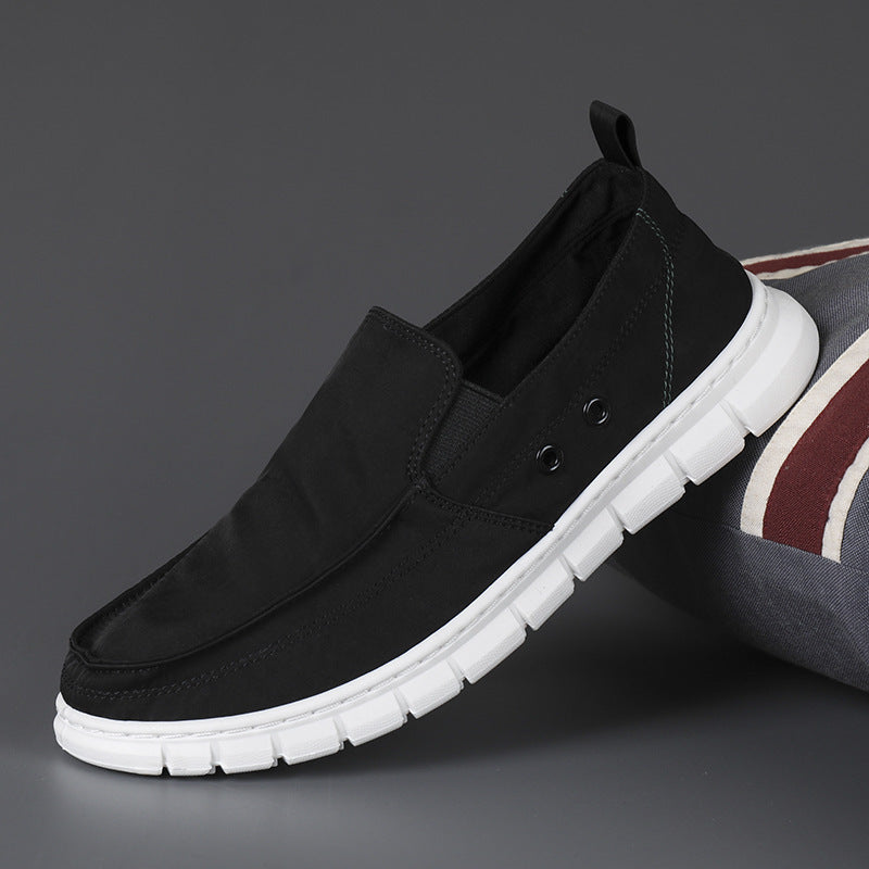 Black slip-on shoe with white sole on a dark background
