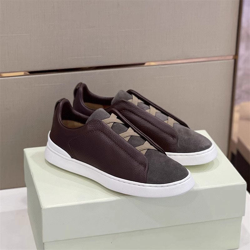 Pair of brown and black sneakers on a light green box with a neutral background