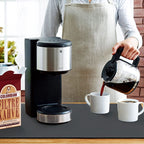 Person pouring coffee from a carafe into a mug next to a coffee maker and a bag of coffee.
