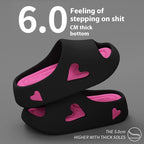 Black clogs with pink hearts on a gray background