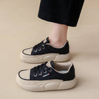 Black and white sneakers worn by a person on a beige background