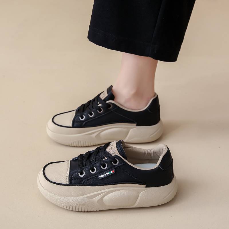 Black and white sneakers worn by a person on a beige background