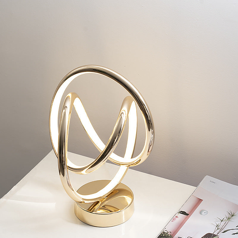 Modern gold table lamp with circular design on a white surface.