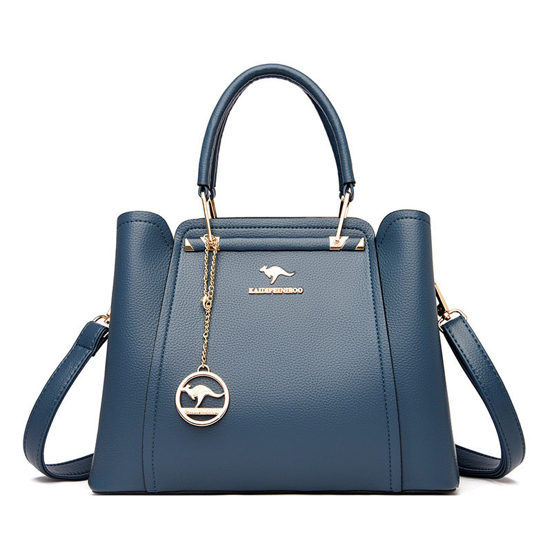 Blue handbag with a gold chain and kangaroo emblem on a white background