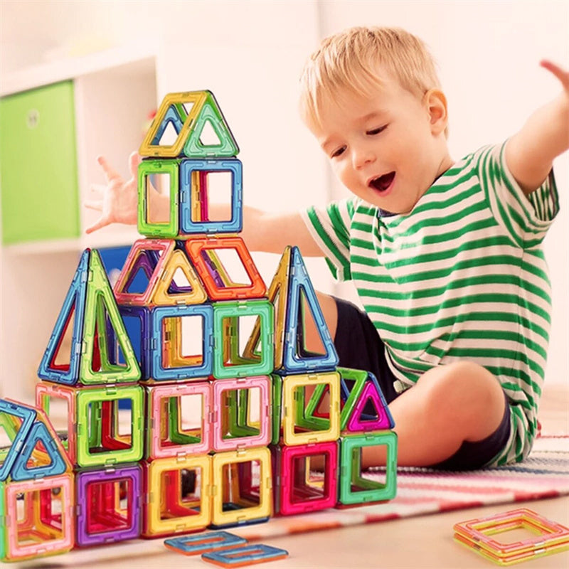 Child playing with colorful magnetic building blocks on a light surface.