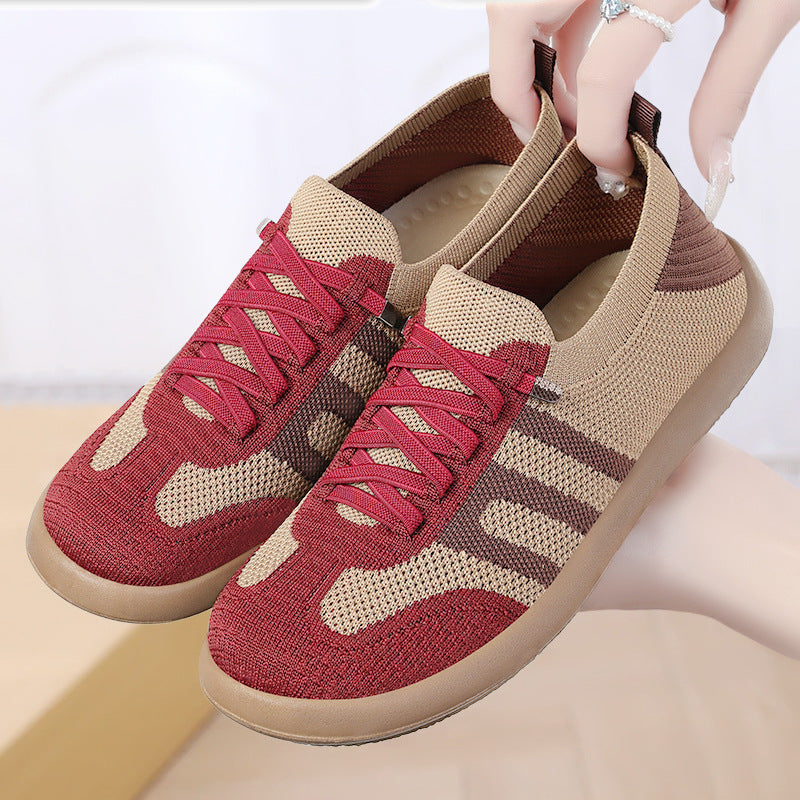Red and beige sneakers with a person holding them on a light background