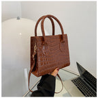 Brown textured handbag held in front of a laptop on a white surface
