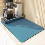 Blue mat in front of a coffee maker on a light-colored surface.