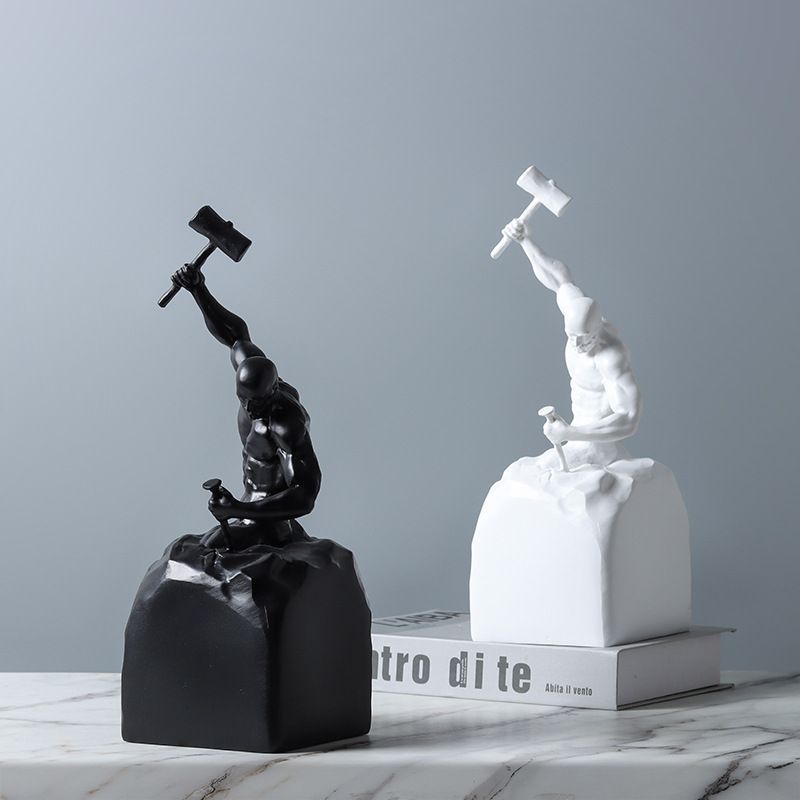 Black and white sculptures of figures with hammers on a gray background