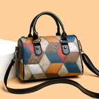 Multicolored patchwork handbag with black handles and strap on a beige background