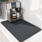 Espresso machine with a cup of coffee on a black mat in a kitchen setting