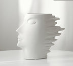 White ceramic vase shaped like a face on a white background