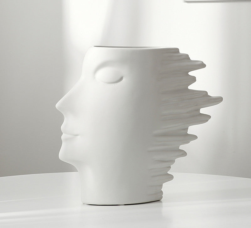 White ceramic vase shaped like a face on a white background