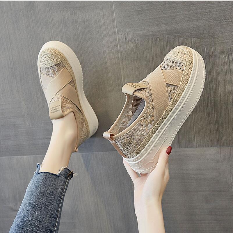 Beige mesh sneakers being held against a gray background