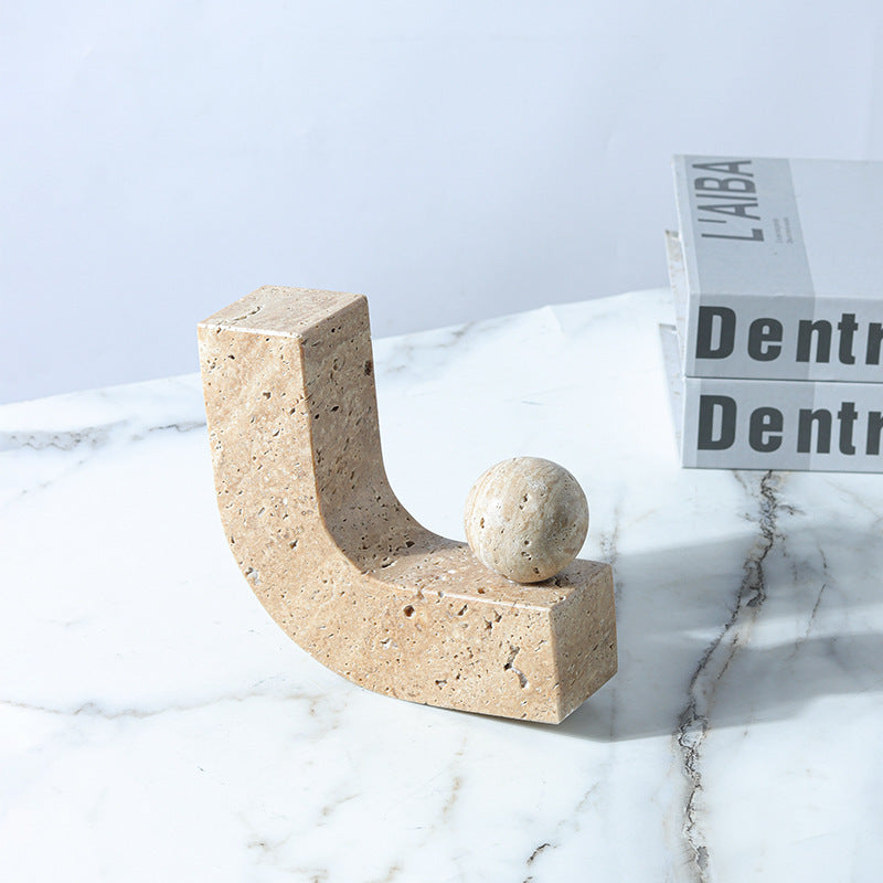 Beige stone sculpture on a marble surface with a newspaper in the background