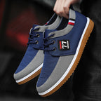 Blue and gray sneakers with a brand logo held by a person against a dark background