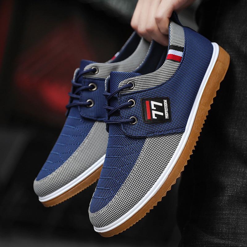Blue and gray sneakers with a brand logo held by a person against a dark background