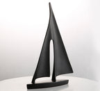 Black abstract sculpture on a white surface with a light gray background