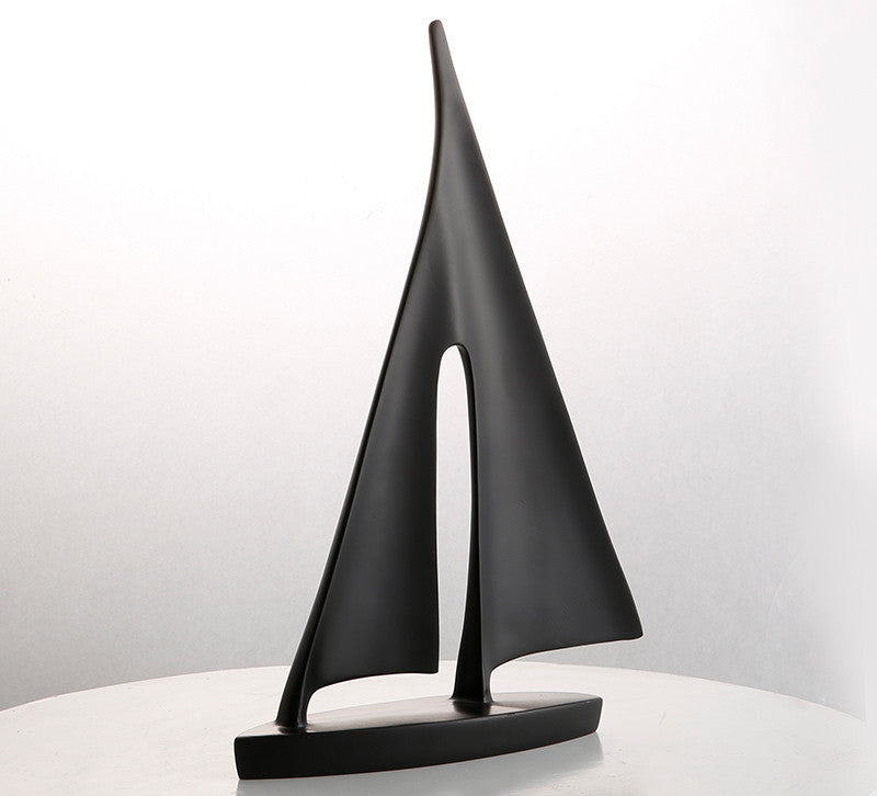 Black abstract sculpture on a white surface with a light gray background