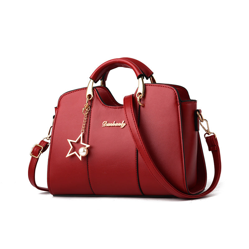 Red handbag with a star charm and gold accents on a white background
