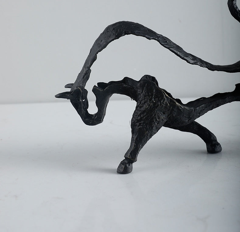 Black metal sculpture of a creature with outstretched wings on a white background