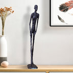 Decorative black sculpture on a wooden surface with a vase and artwork in the background.
