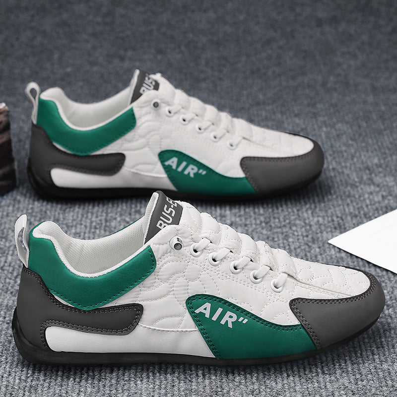 White sneakers with green and black accents on a gray surface