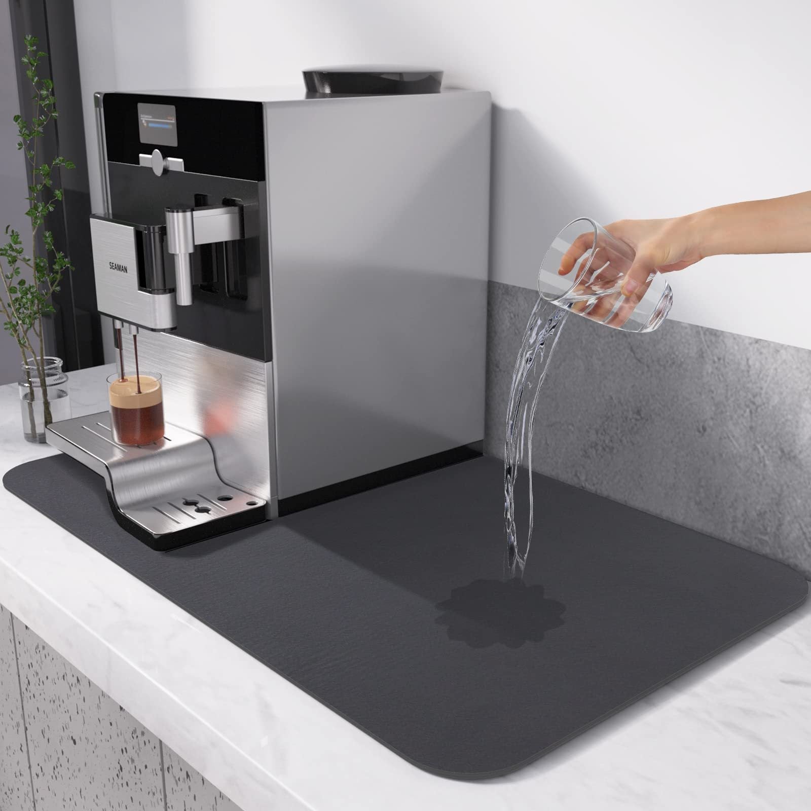 Coffee machine with a black mat on a white countertop, showing water spillage.