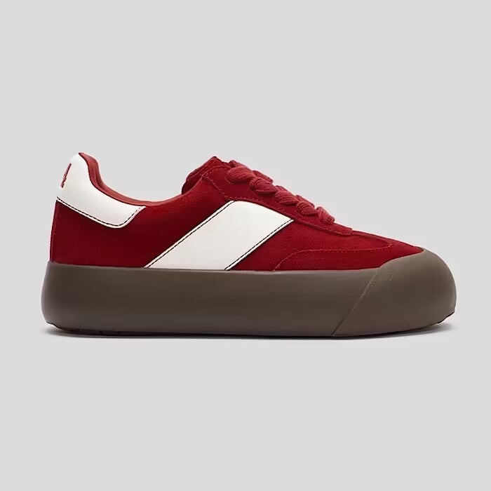 Red and white sneaker with a brown sole on a light gray background