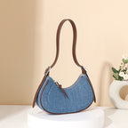Blue denim handbag with brown leather strap on a beige background