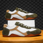 Pair of green and brown sneakers on a wooden surface with a black grid background