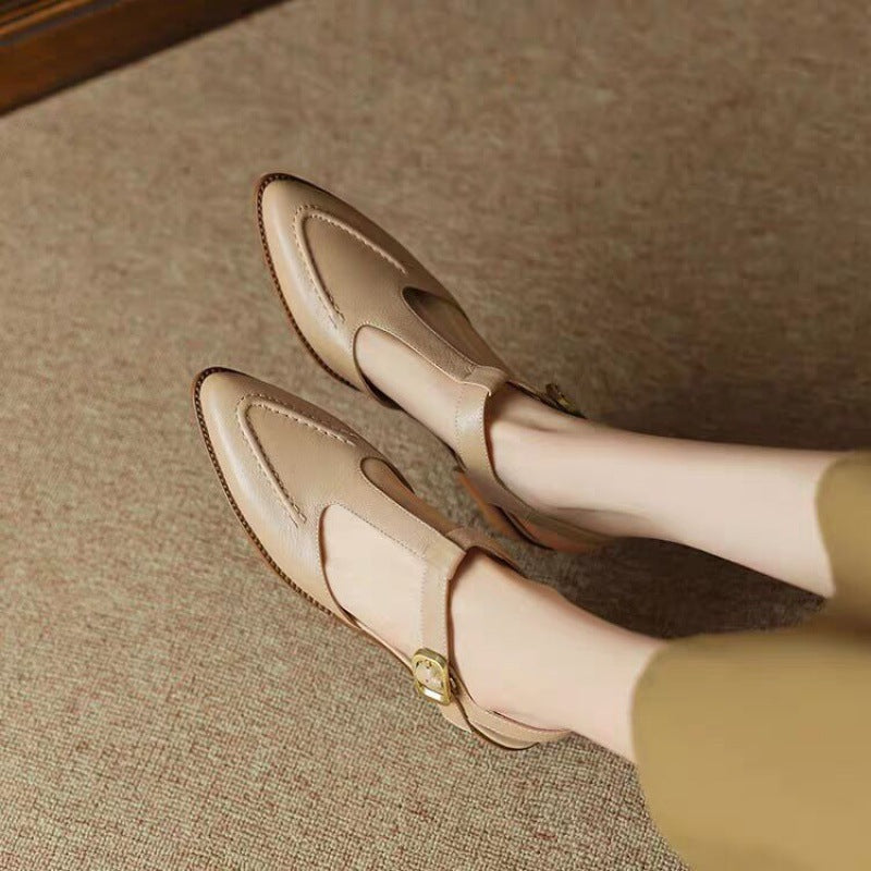 Beige loafers worn by a person on a textured surface
