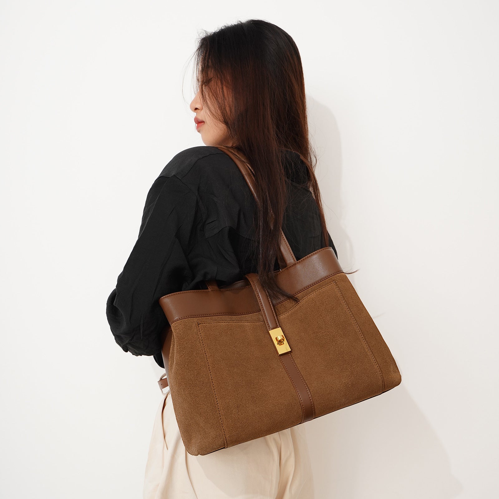 Person carrying a brown tote bag on a white background