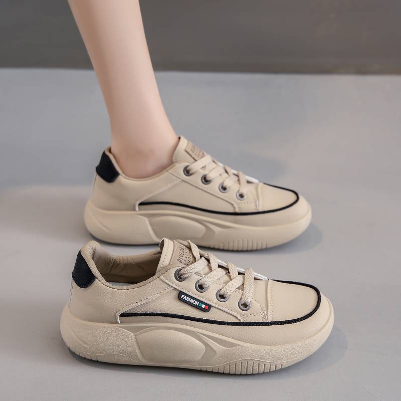 Beige sneakers with black accents on a gray background