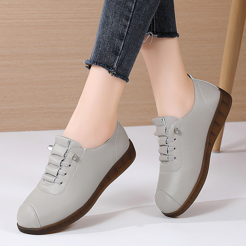 Light gray sneakers with brown soles worn with blue jeans on a neutral background