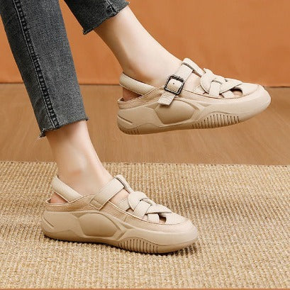Beige sandals worn with gray pants on a brown background